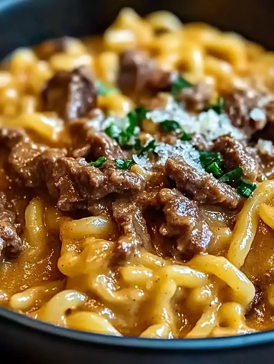 Pasta con salsa cremosa, trozos de res y hierbas frescas en un bol. Se ve apetitoso y listo para comer.