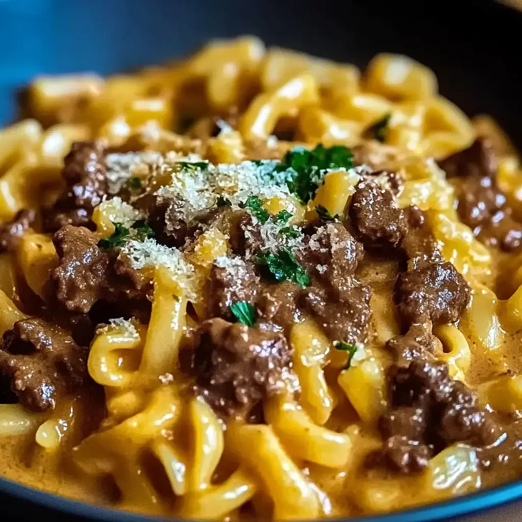 Pasta cubierta de salsa marrón cremosa, con queso rallado y hierbas frescas por arriba. Se ve súper apetecible.