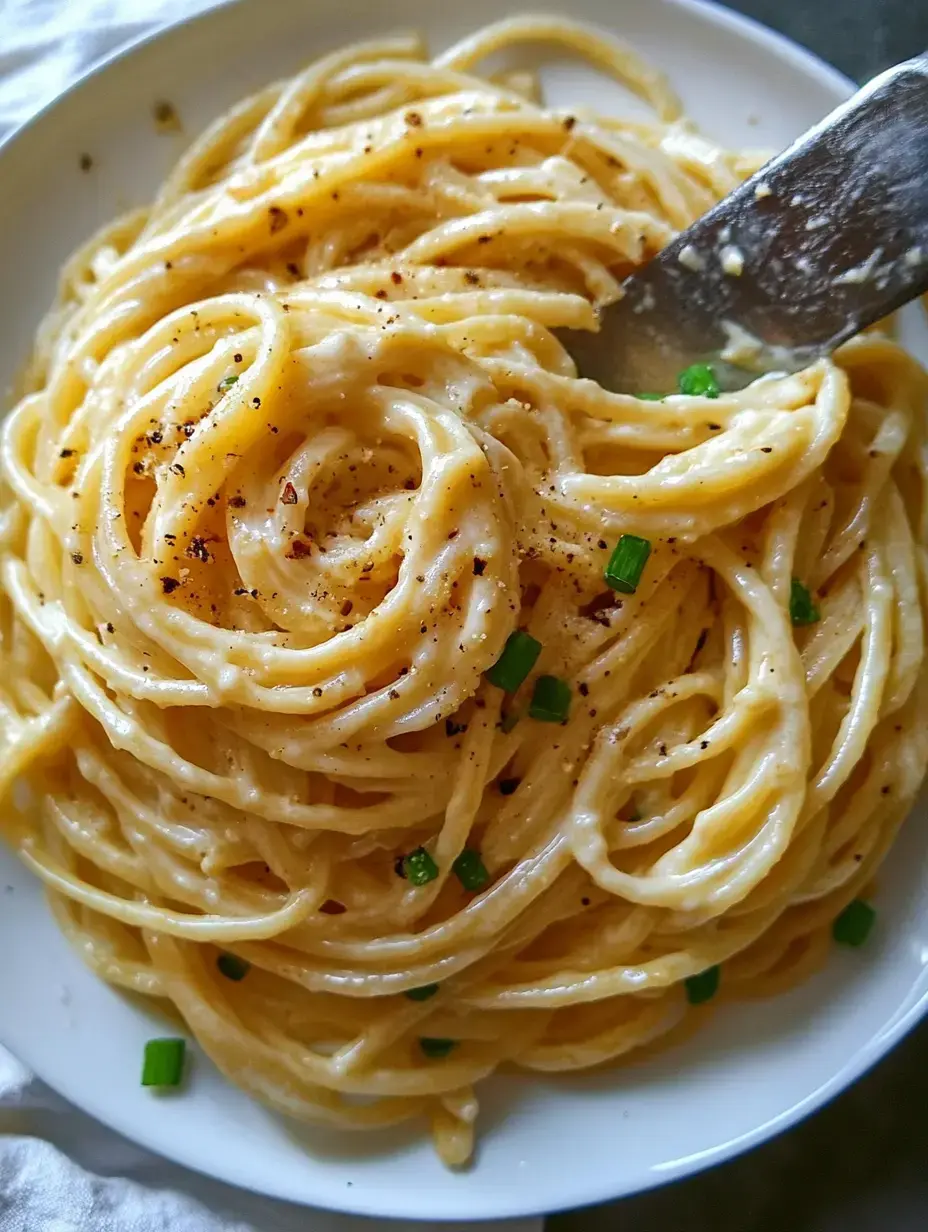 Vista cercana de pasta cremosa con pimienta negra y cebolla verde picada.