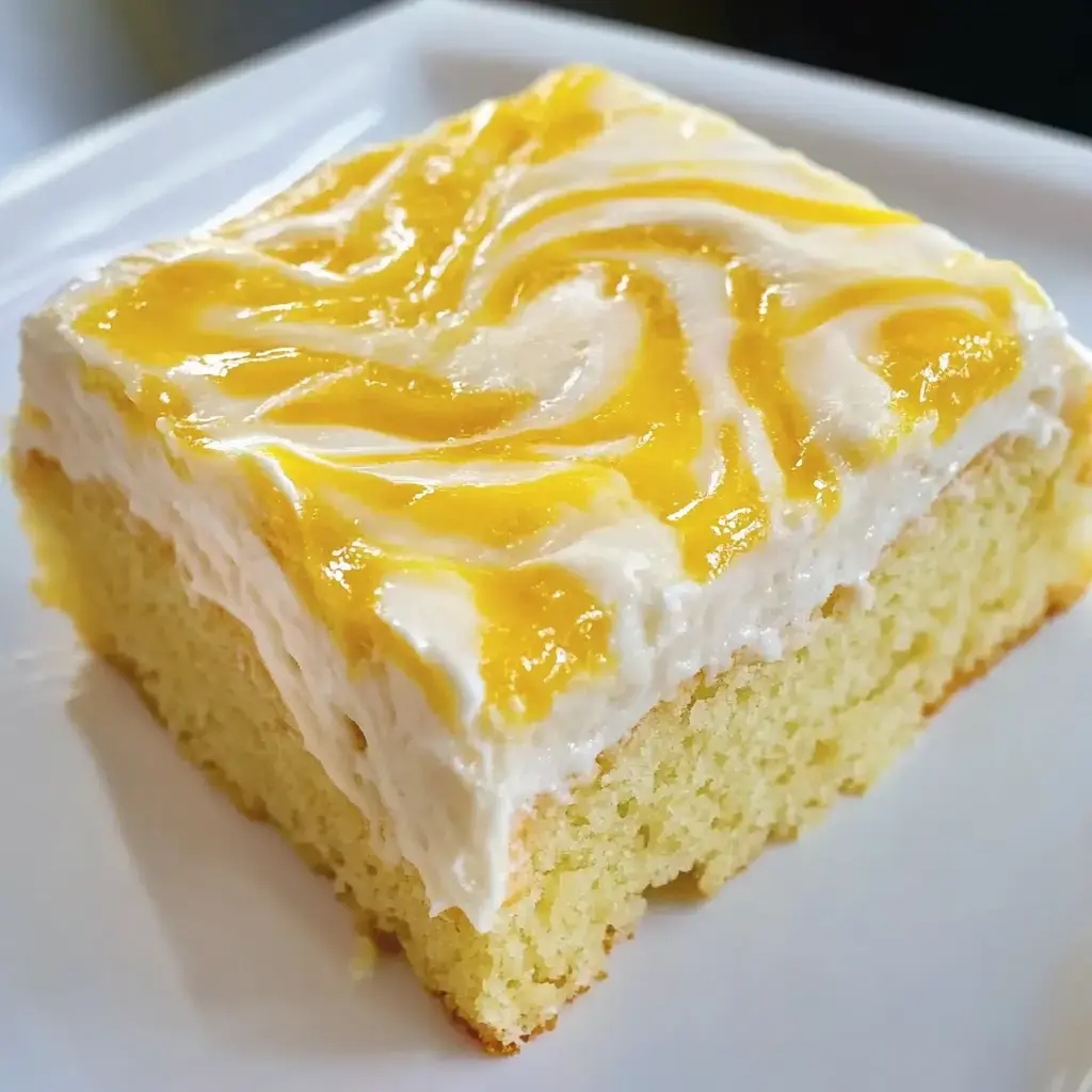 Un bizcocho con una glaseado cremoso blanco-amarillo sobre un plato blanco.