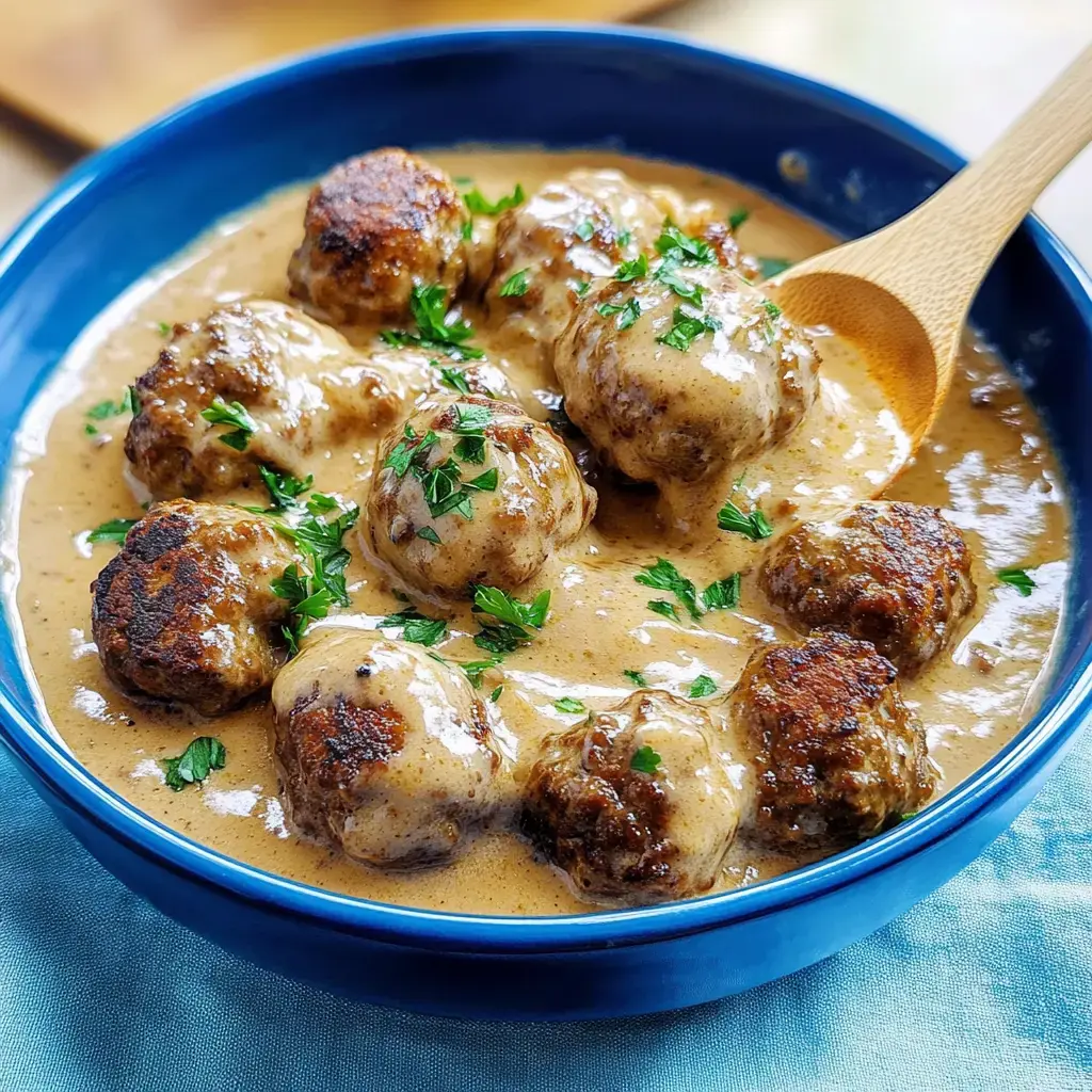 Un plato de albóndigas en salsa cremosa, decorado con perejil fresco.