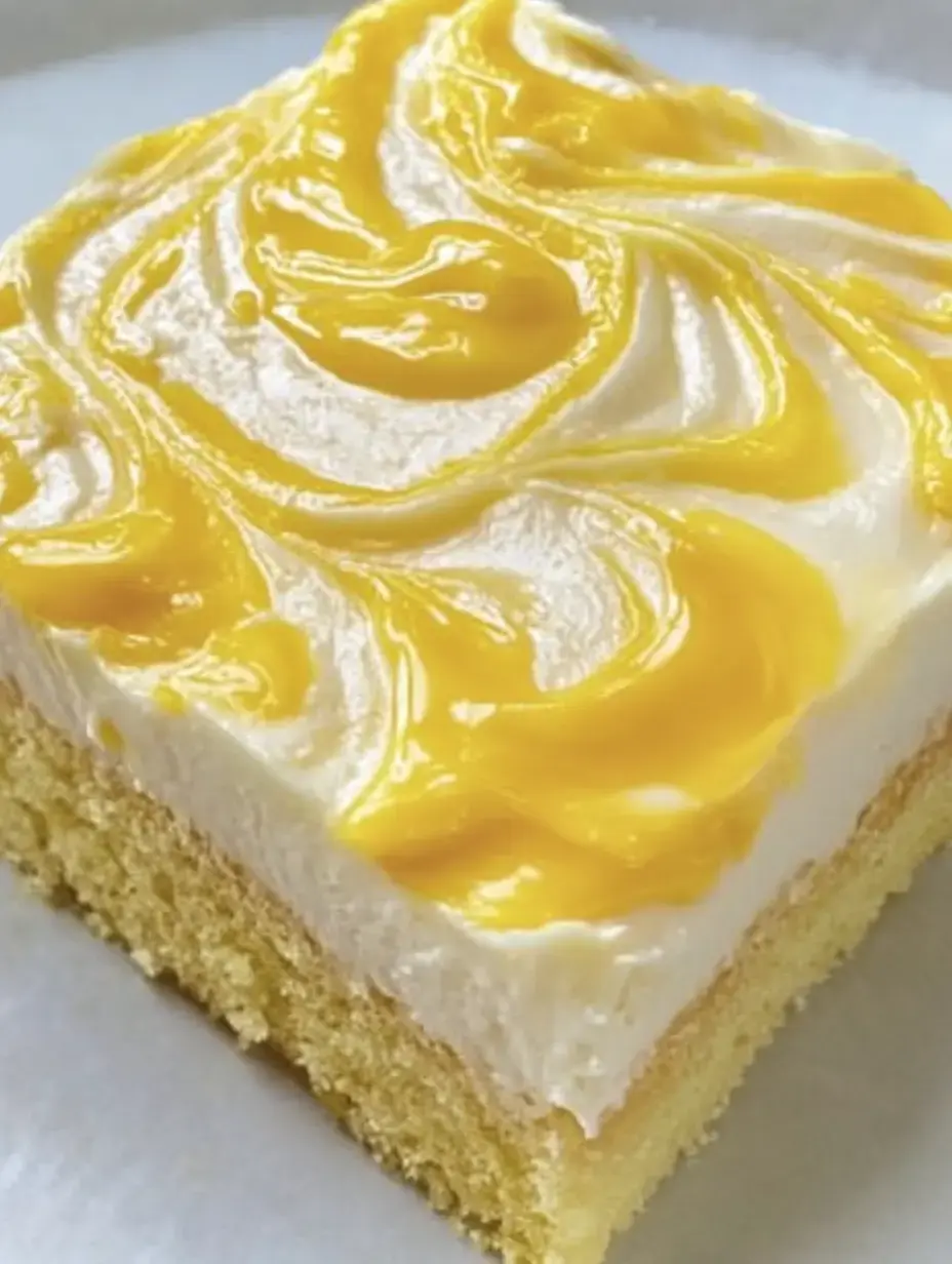 Trocito de pastel cubierto con glaseado blanco y salsa amarilla arriba.
