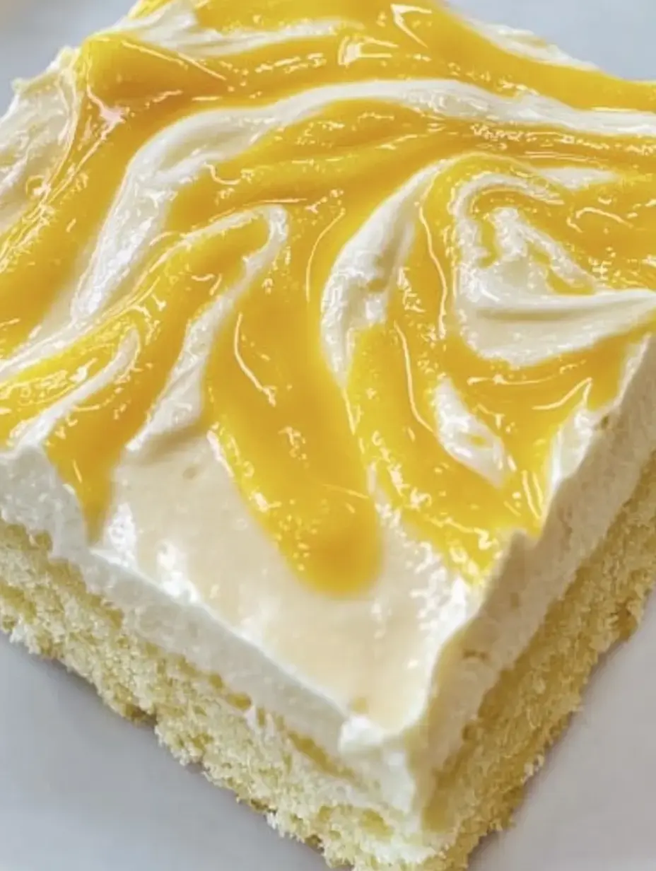 Porción de pastel con glaseado blanco y salsa de frutas amarilla encima.