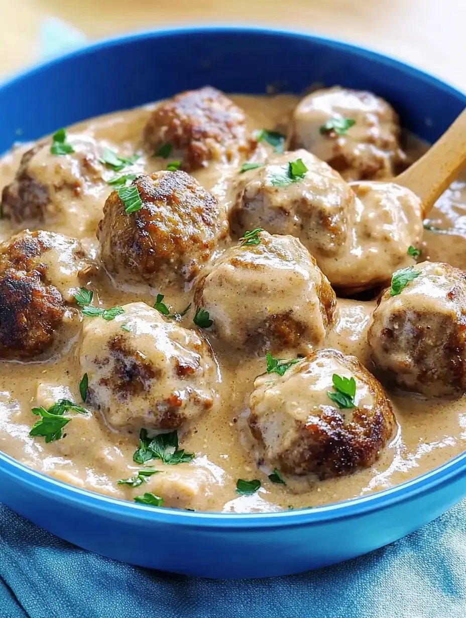 Bowl con albóndigas suecas en salsa cremosa, decoradas con perejil fresco.