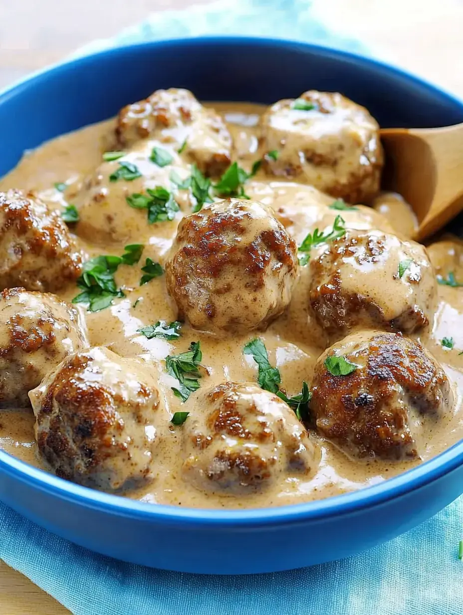 Plato con albóndigas jugosas en salsa cremosa, coronadas con perejil.