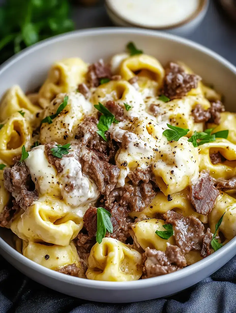 Un bol de tortellini cremosos con carne sazonada y perejil fresco.