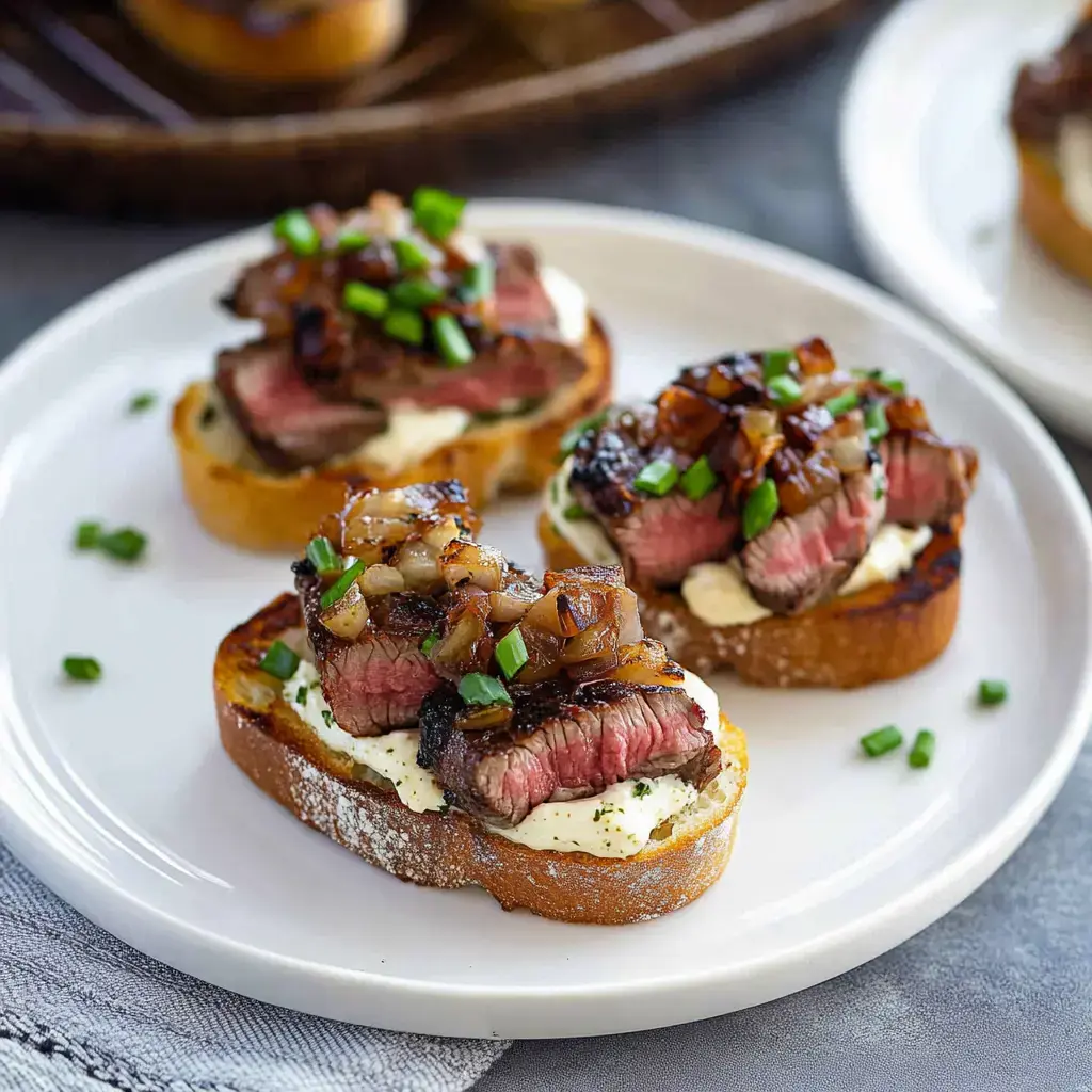 Un plato con pan tostado cubierto de carne asada, crema, cebollas caramelizadas y cebolla verde picada.