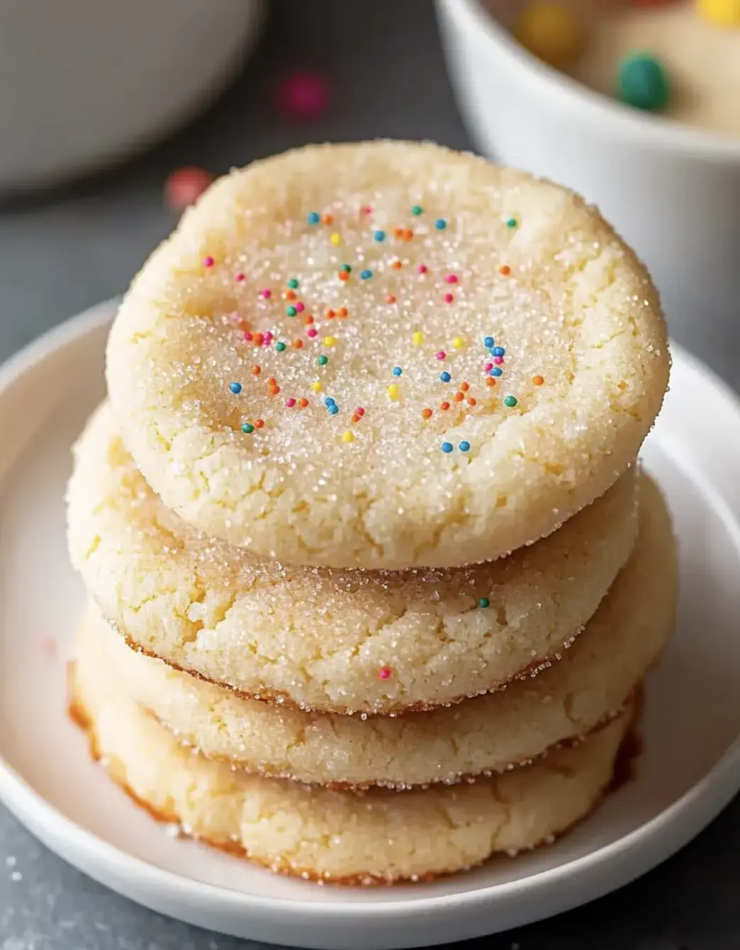 Torre de cuatro galletas de azúcar con confites de colores sobre un plato blanco.