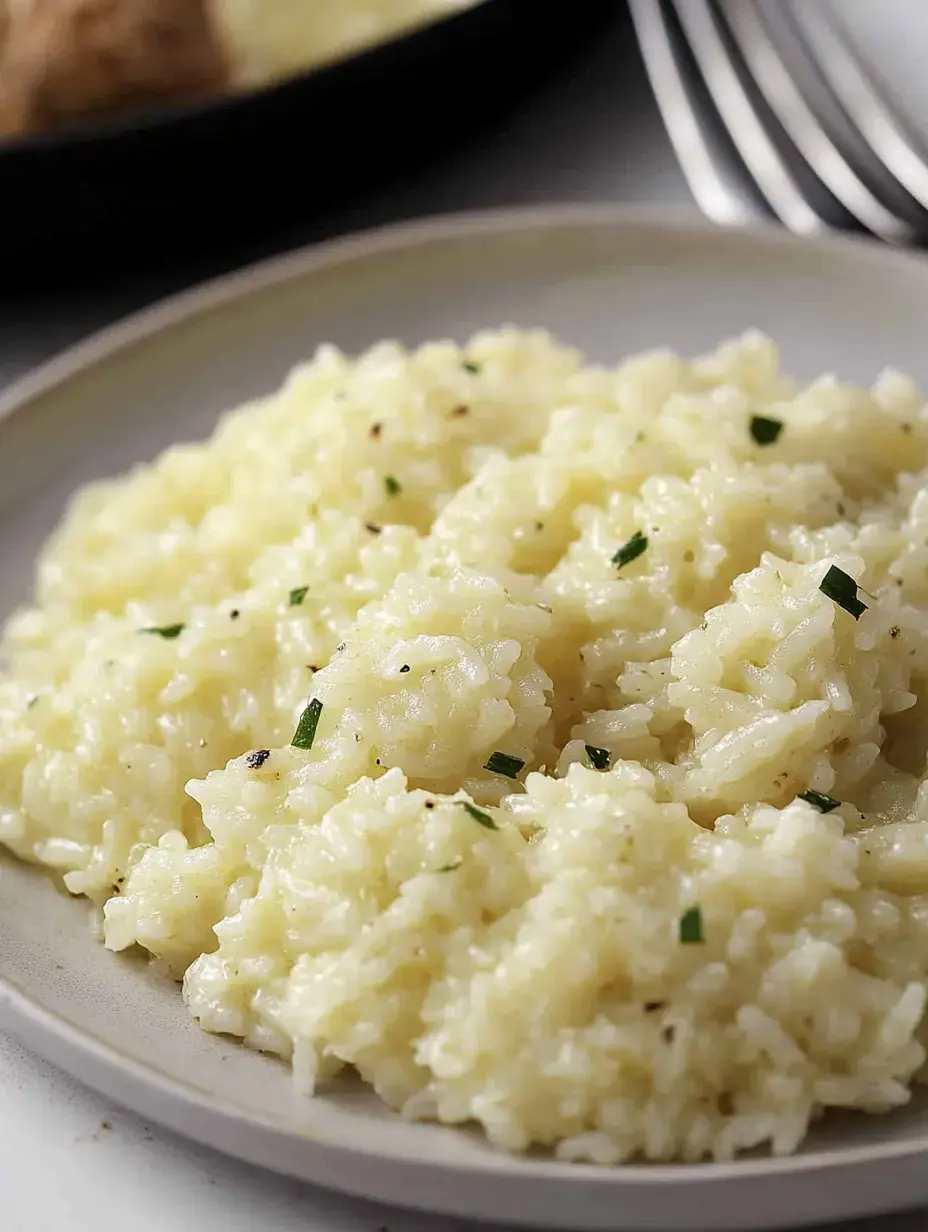 Un plato de arroz cremoso con hierbas por encima en un plato claro.