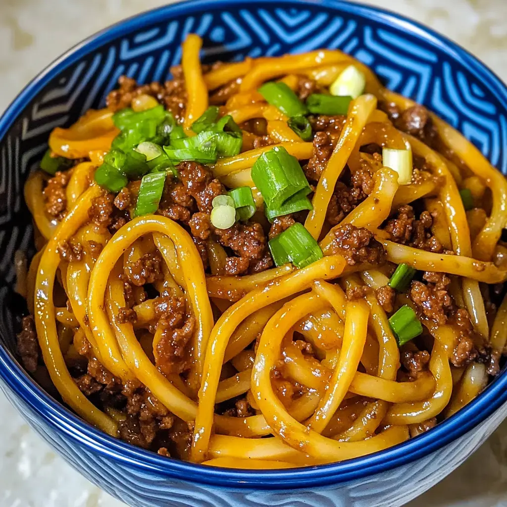Un bol con fideos, carne molida y cebollín picado por encima.