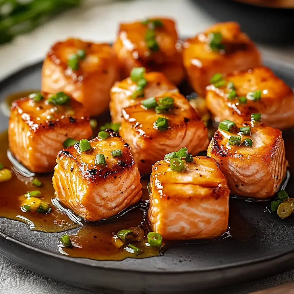 Un plato de cubos de salmón glaseados decorados con cebollín picado.
