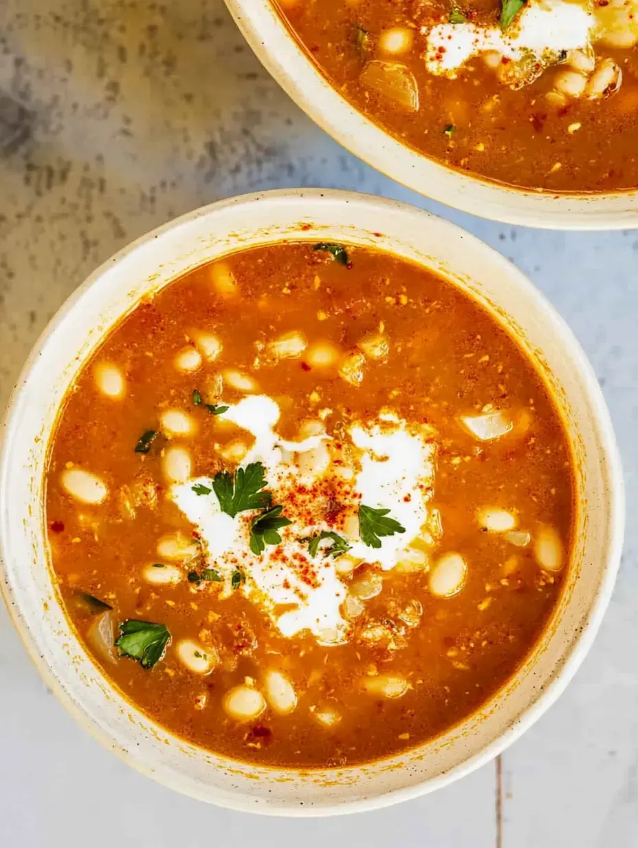 Vista cercana de dos bowls de sopa, con crema, perejil y pizca de especias arriba.