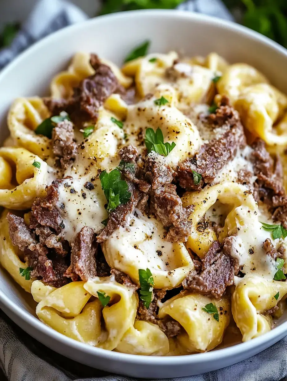 Pasta en un tazón con tiras de carne, queso derretido y un poquito de perejil.
