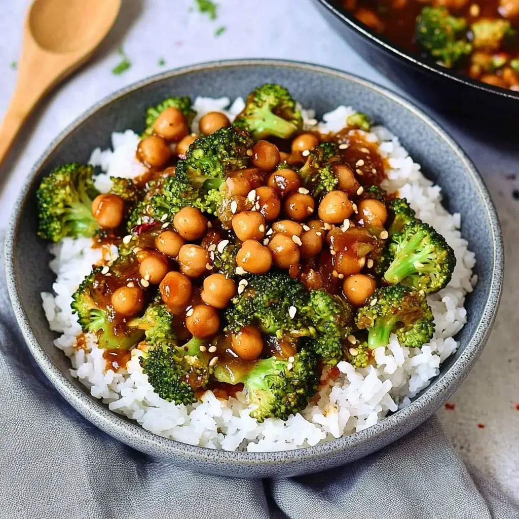 Un cuenco con arroz blanco, acompañado de brócoli, garbanzos y salsa deliciosa.