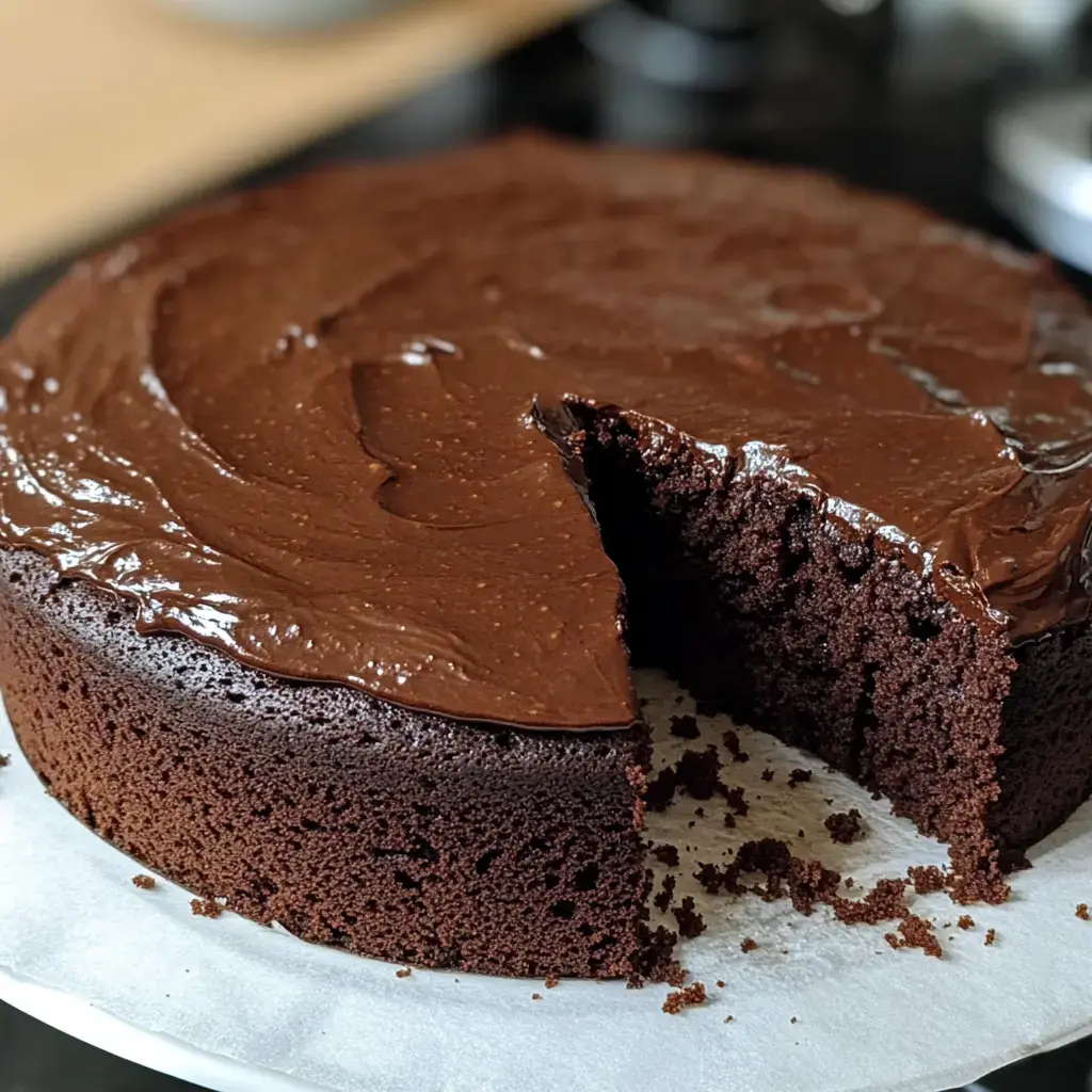 Un pastel de chocolate brillante y jugoso, al que le falta una rebanada.