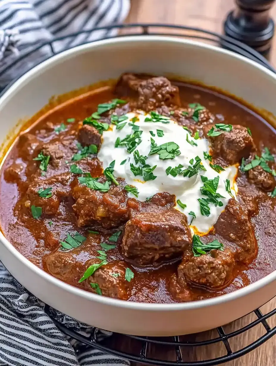 Plato de carne jugosa en salsa con hierbas frescas y crema encima.