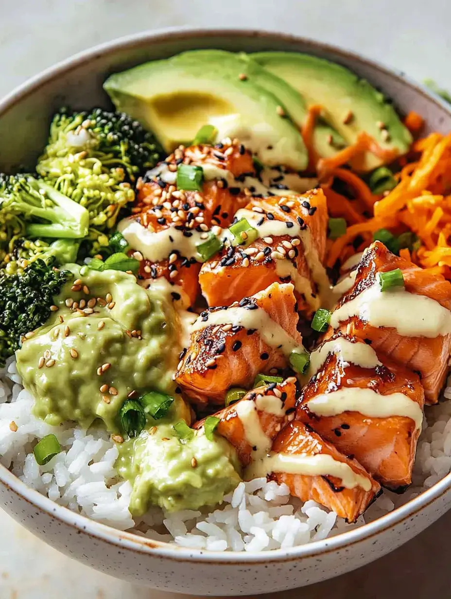 Un cuenco con arroz, salmón a la parrilla, brócoli, rodajas de aguacate, zanahorias ralladas, guacamole y una salsa cremosa, decorado con sésamo y cebolletas.