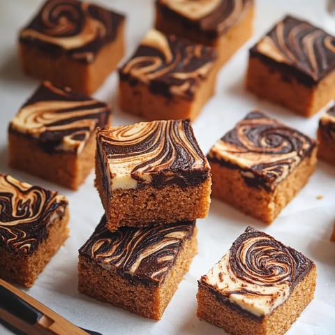 Cubos cuadrados de bizcocho con un diseño marmoleado de chocolate colocados sobre papel de horno.